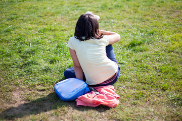 Fototapeta premium Girl resting on the grass. A child is sitting on the lawn.