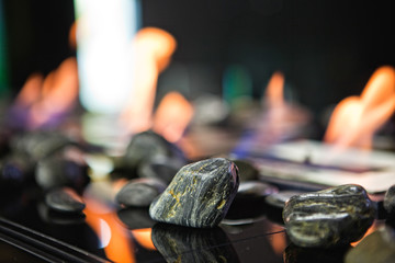 Bioethanol  portable fireplace burning at home, for live fire at home, no chimney and mantelpiece is needed. Liquid bio ethanol burns in cup. Round shaped glasses with stones inside. Stones close up