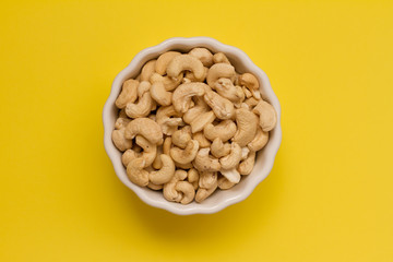 cashew nuts in a white ceramic bowl on a yellow background. the concept of proper nutrition and health. Healthy food and snack, organic vegetarian food. Walnuts, pistachios, almonds, hazelnuts