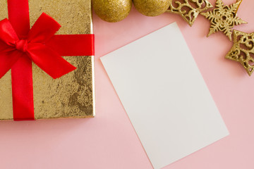 gold box on pink background with red bow. Christmas decorations on the Christmas tree, snowflake, Golden balls, white paper, letter. christmas present. space for text. background for postcard and bann