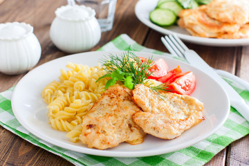 Chicken breast in batter with pasta on a white plate, selective focus