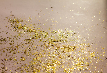 small gold sequins scattered on a pink background. background with beautiful shadow. poster. postcard view. space for your text. holiday. Christmas, women's day.