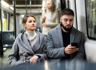 Man and woman using phone inside tram