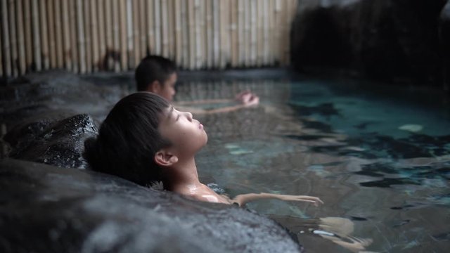 4k Close up two young asian boy relax in hot water onzen