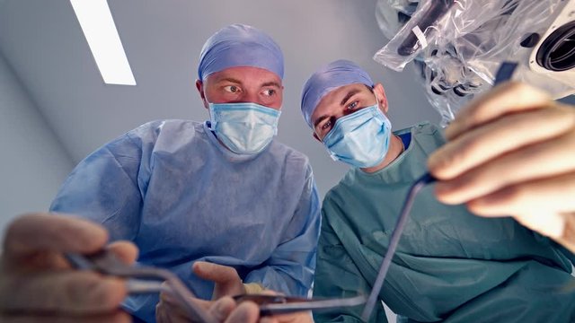 Bottom view of surgeons on operation. Team of surgeons over the operating table