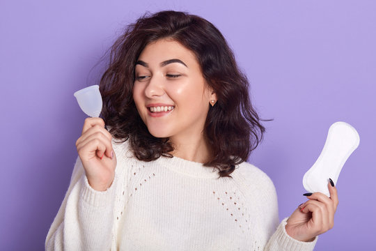 Woman holding menstrual cup and sanitary pad in hands. Feminine hygiene alternative product instead of tampon during her period. Menstruation, critical days, zero waste, eco, ecology concept.
