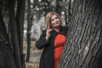 Middle age woman of plus size, American or European appearance walks in the city enjoying life. Lady with excess weight, stylishly dressed at the center of the city. Natural beauty