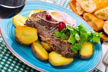 Beef steak with  baked potatoes served at plate with greens