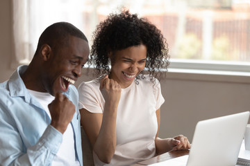 Overjoyed multiracial couple triumph with good online news