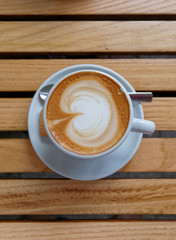 hot Italian cappuccino coffee cup on wooden table background, top view