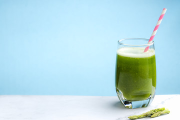 Healthy green smoothie asparagus on cutting board and blue background. food and drink for health concept.
