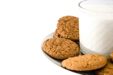 oatmeal cookies in a plate and a glass of milk on a white background. Side view.