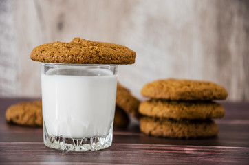 oatmeal cookies and a glass of milk on a wooden background.