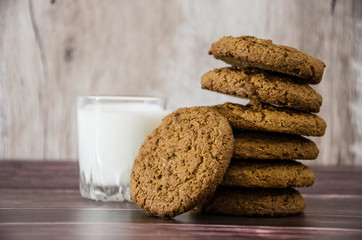 oatmeal cookies and a glass of milk on a wooden background.