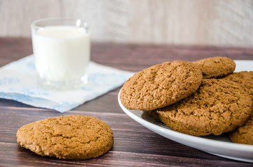 oatmeal cookies and a glass of milk on a wooden background.