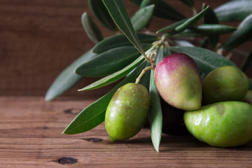 natural olives with leaves on wooden background