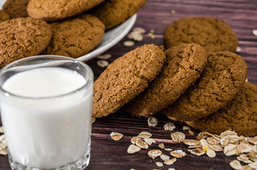 oatmeal cookies and a glass of milk on a wooden background.