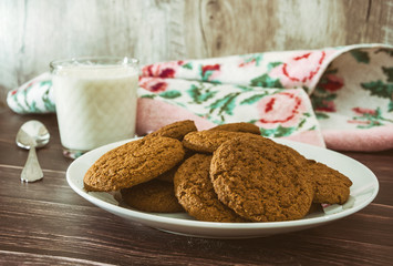 oatmeal cookies and a glass of milk on a wooden background.