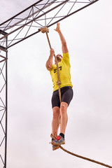 young man climbing a rope of knots in a Spartan race