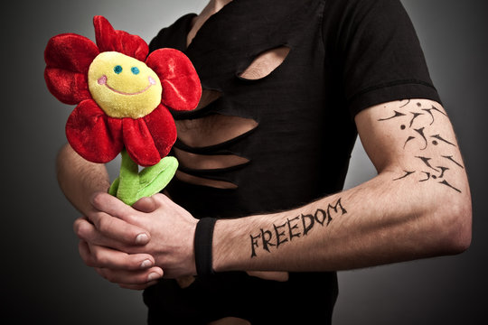 Young man in modern black clothing holding flower toy