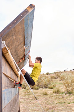 young man climbing a wooden wall in a Spartan race