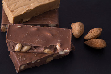 Turron, typical Christmas sweet in Spain. Almond nougat on black stone background..
