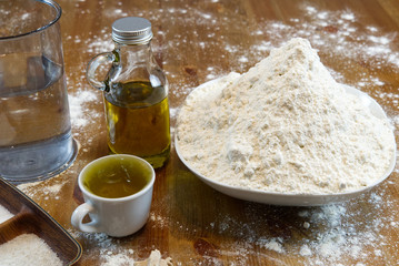 ingredients for making Italian pizza dough at home. flour, salt, sugar, yeast, olive oil and water