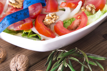 lettuce, nuts and tomato salad with tape measure, healthy diet concept