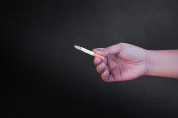 Hand is holding a cigarette on black background,No smoking. Quitting from addiction concept.