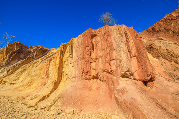 Vivid colors of Ochre Pits a minerals rock formation ochre on dry creek in West McDonnell Ranges. Popular destination in Northern Territory, Australia. Ochre is used by Aborigine people for ceremonies