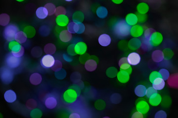 Festive green blue and purple bokeh blurred lights on a dark background
