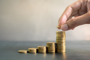 Hand stacking gold coins on black wooden table. Business, finance, marketing, e-commerce concept...