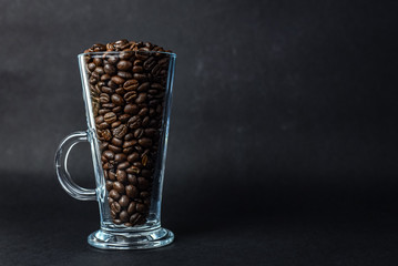 Coffee beans in a latte glass against a black background