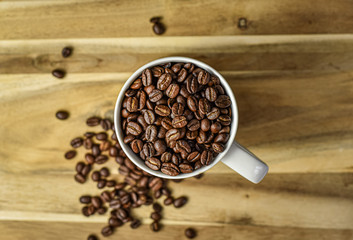 Coffee beans in a white coffee mug on a wooden background