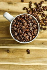 Coffee beans in a white coffee mug on a wooden background