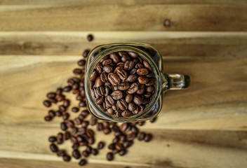 Coffee beans in a glass coffee mug on a wooden background