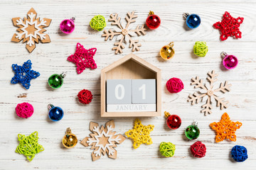 Top view of calendar on Christmas wooden background. The first of January. New Year toys and decorations. Holiday concept