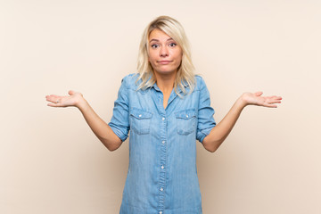 Young blonde woman over isolated background having doubts with confuse face expression