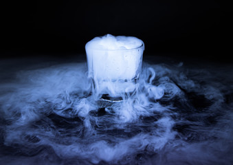 The smoke from dry ice in a glass, black background.