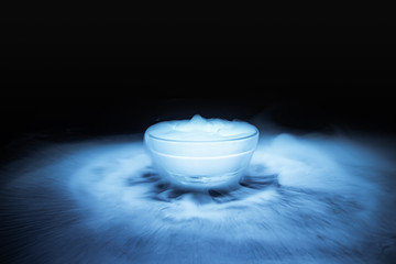 The smoke from dry ice in a glass bowl black background.