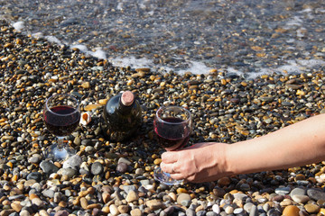 Romantic day with glasses of red wine, on the beach on a Sunny autumn day. Waves and sea in the background. The concept of the wedding