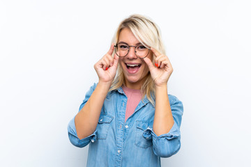Young blonde woman over isolated white background with glasses and surprised