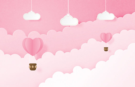 Valentine's day banner with heart shape hot air balloon floating in the sky and hanging clouds in paper cut style. Digital craft paper art concept.