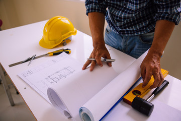 architect man reading with blueprint to build houses. After agreeing the employment price the cost of construction and repair real estate