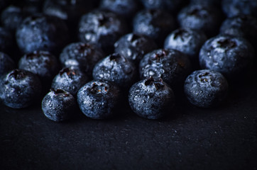 Blueberries close up macro on a black slate background.