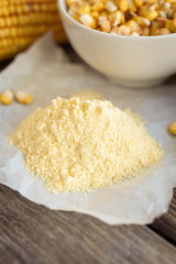 Corn flour and corn on the cobs on wooden background