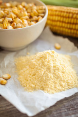 Corn flour and corn on the cobs on wooden background