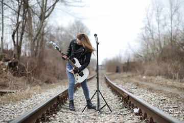  A rock musician girl in a leather jacket with a guitar