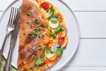 Omelette with zucchini, lamb's lettuce, tomatoes and red pepper on plate. Frittata - italian omelet.