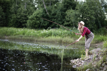 Girl by the river with a fishing rod